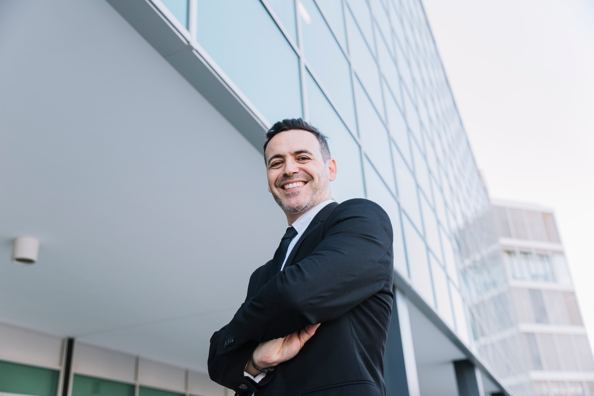 Empresario pyme sonriendo frente a un edificio de oficinas